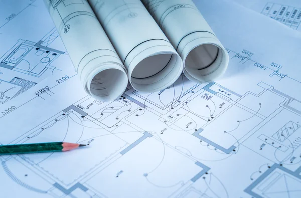 Architectural blueprints and blueprint rolls and a drawing instruments on the worktable Royalty Free Stock Images