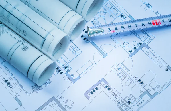 Architectural blueprints and blueprint rolls and a drawing instruments on the worktable — Stock Photo, Image