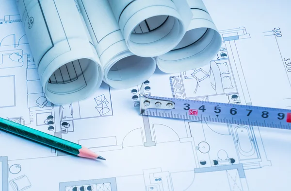 Architectural blueprints and blueprint rolls and a drawing instruments on the worktable — Stock Photo, Image