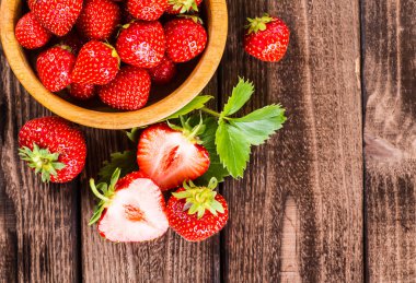 Çilek ahşap arka plan üzerinde. Çilek yeşil yaprakları ile.