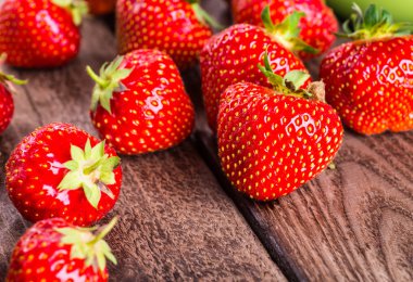 Çilek ahşap arka plan üzerinde. Çilek yeşil yaprakları ile.