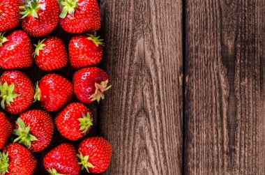 Çilek ahşap arka plan üzerinde. Çilek yeşil yaprakları ile.