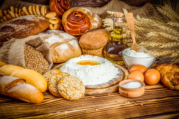 Pão fresco e trigo na madeira — Fotografia de Stock