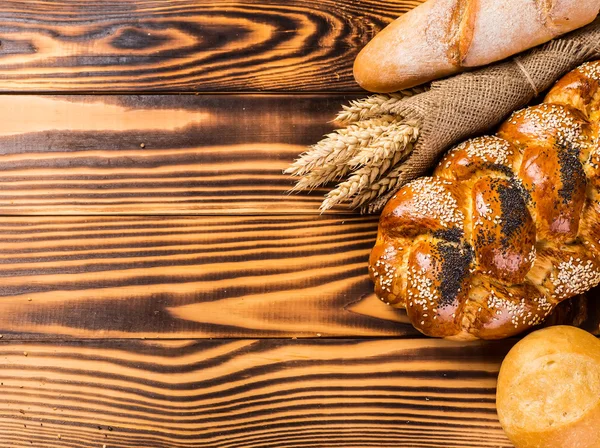 Assortment of baked bread on wooden table background — Stock Photo, Image