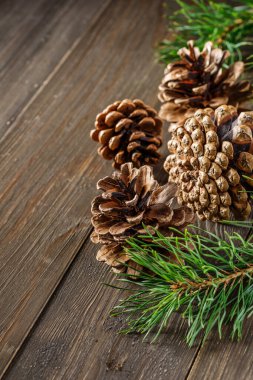 Çam kozalağı ve yeşil dal, ahşap masa üzerinde kar, mesaj için kopyalama alanı. Noel kartı. Ahşap arka planda çam kozalakları.