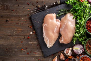 Katalog için çekim. Taze çiğ tavuk göğsü parçaları, pişirmeye hazır, domates ve maydanozla birlikte. Üst görünüm