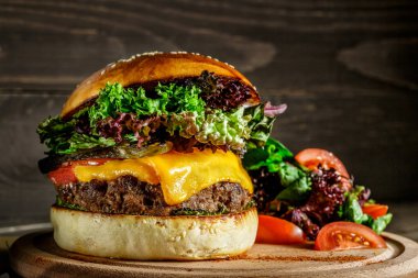 Ev yapımı taze burger, sığır eti, soğan, domates, marul, peynir ve baharat. Koyu arkaplanda hamburger.