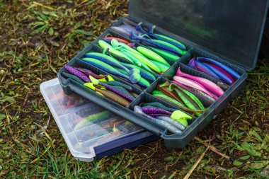 Balık tutmak için yem ve ekipman dolu büyük bir balıkçı çantası. Arka planda balık yemi ve aksesuarları var..