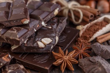 Tahta bir masa üzerinde nane yaprağıyla dilimlenmiş çikolata yığını. Beyaz, siyah ve sütlü çikolata çeşitleri. Tatlı yemek fotoğraf konsepti.