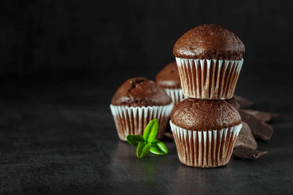 Chocolate cupcake with icing and chocolate bar in Dark lighting,Homemade delicious chocolate muffin on wooden background close-up