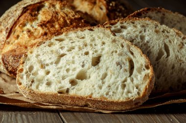 Ekmek, kırsal ahşap arka planda dilimlenmiş geleneksel ekşi ekmek. Geleneksel mayalanmış ekmek pişirme yöntemleri kavramı. Sağlıklı yemek..