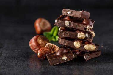 Nane yaprağıyla bir yığın çikolata dilimi. Fındık ve badem sütü ve siyah çikolata parçaları. Tatlı yiyecek fotoğraf konsepti. Kırık çikolata parçaları.