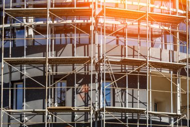 Yeni bir apartman bloğunda çalışma platformları sağlayan kapsamlı yapı iskeleleri, inşaat halindeki uzun binalar, Yeni Bina İnşaat Alanı