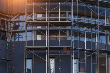 Yeni bir apartman bloğunda çalışma platformları sağlayan kapsamlı yapı iskeleleri, inşaat halindeki uzun binalar, Yeni Bina İnşaat Alanı