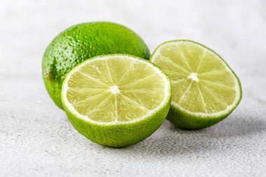 İkiye bölünmüş yeşil kireç ve beyaz arka planda izole edilmiş dilimler. Sağlıklı yeşil gıdalar - alternatif tıp vitaminler, besinler ve insan refahı için süper yiyecekler içeren dengeli bir diyet içerir..