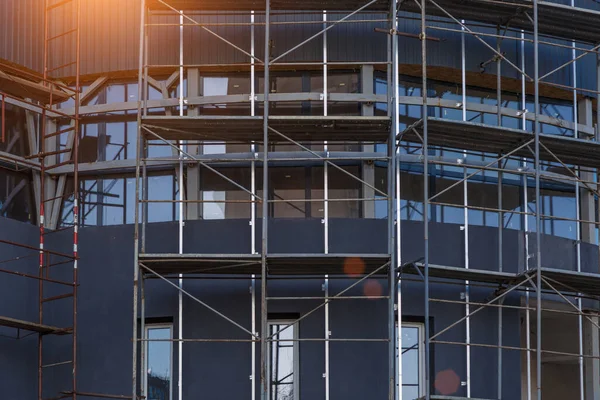 Extensive scaffolding providing platforms for work in progress on a new apartment block,Tall building under construction with scaffolds,Construction Site of New Building