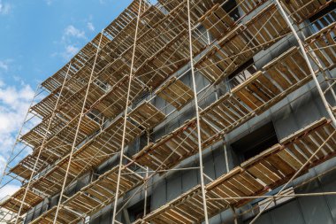 Yeni bir apartman bloğunda çalışma platformları sağlayan kapsamlı yapı iskeleleri, inşaat halindeki uzun binalar, Yeni Bina İnşaat Alanı