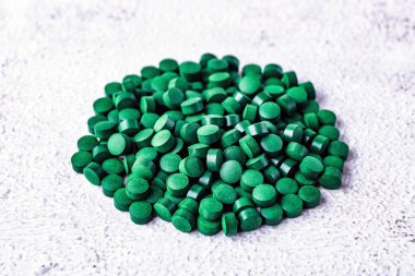 Akvaryum balığı yemi kapağı. Tropikal akvaryum balıklarını beslemek için granül yığını, yan görüş. Koyu yeşil yuvarlak sarmal akvaryum tabletleri.