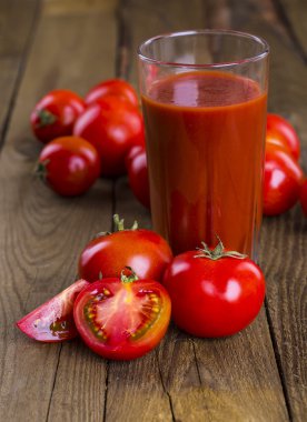 Bardak domates suyu ahşap ahşap masa üzerinde arka plan bitkiler