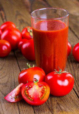 Bardak domates suyu ahşap ahşap masa üzerinde arka plan bitkiler