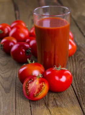 Bardak domates suyu ahşap ahşap masa üzerinde arka plan bitkiler