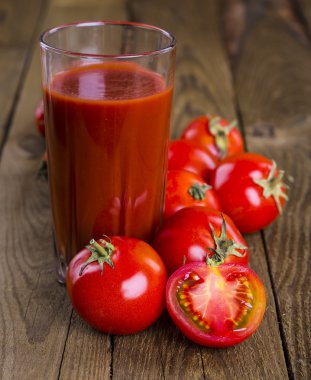 Bardak domates suyu ahşap ahşap masa üzerinde arka plan bitkiler