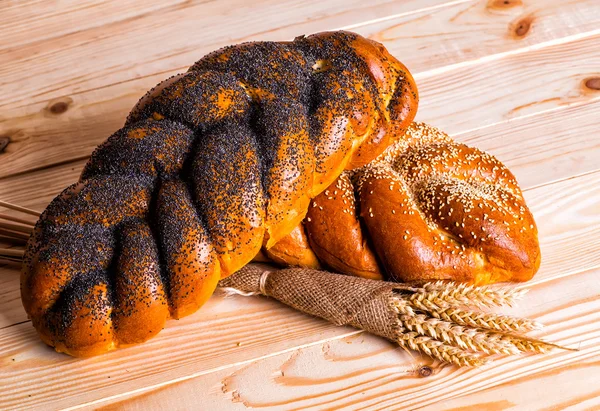 Haşhaş ve bir tahta üzerinde susam ile iki bütün taze challah ekmek 