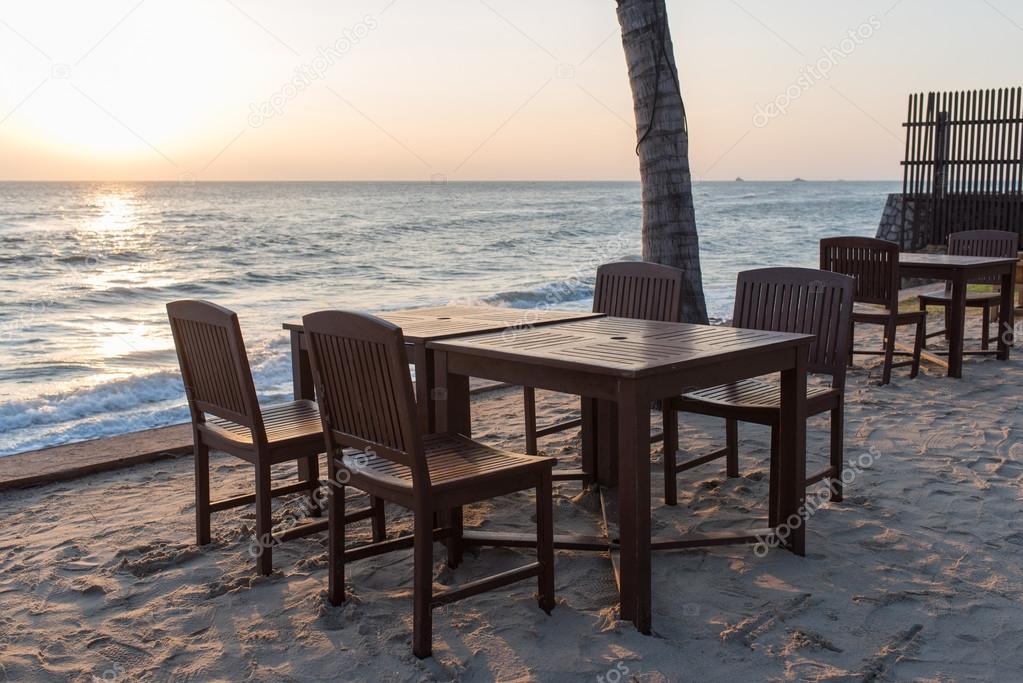 Wooden chairs on the beach at sunrise with a tropical sea
