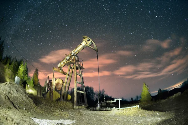 典型的罗马尼亚水泵晚上在乌克兰喀尔巴阡山脉的山坡上工作 星星和银河的星座象征着地球矿物资源的古老历史 — 图库照片