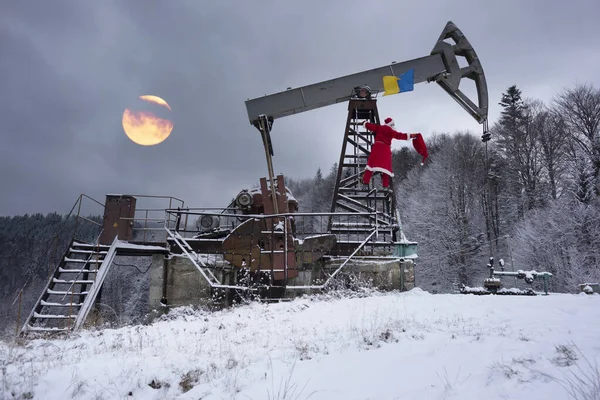 在喀尔巴阡山脉冬季的山上 圣诞老人在装有乌克兰国旗的油泵下给石油和天然气工人带来了一袋礼物 祝您新年快乐 — 图库照片
