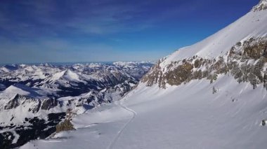 Dağların panoramik manzarası, İsviçre Alpleri 'ndeki Glacier 3000' deki kayakçıları zirveye taşır.