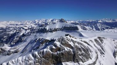 People Walking Across the Suspension Bridge on Glacier 3000 with Cable Car Station and Peak Walk in the Swiss Alps.