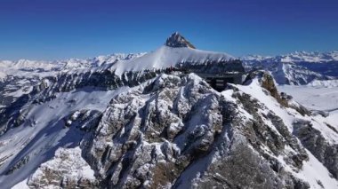 People Walking Across the Suspension Bridge on Glacier 3000 with Cable Car Station and Peak Walk in the Swiss Alps.