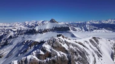 People Walking Across the Suspension Bridge on Glacier 3000 with Cable Car Station and Peak Walk in the Swiss Alps.