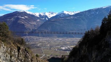 Passerelle Farinet üzerinden yürüyen turistler, güzel güneşli bir günde İsviçre Alpleri manzaralı Salentse Vadisi 'nin üzerindeki tahta köprü.