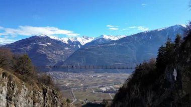 Passerelle Farinet üzerinden yürüyen turistler, güzel güneşli bir günde İsviçre Alpleri manzaralı Salentse Vadisi 'nin üzerindeki tahta köprü.