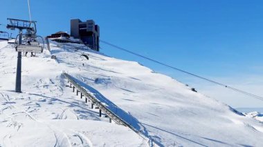 Kışın İsviçre Alpleri 'ndeki kar kaplı ormanlar ve dağ yamaçlarının üzerinden Buzul 3000' e yükselen teleferiğin görüntüsü