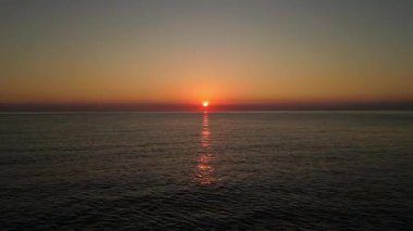 Akdeniz ve güney Fransa 'daki Esterel dağları üzerindeki hava gündoğumu, dalgalı su yüzeyine yansıyan turuncu güneş ışığı, altın gökyüzü ve huzurlu kıyı manzarası