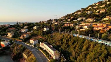 Saint Raphael, Fransız Rivierası yakınlarındaki Esterel Dağları 'ndaki Antheor Viaduct' ı geçen bir trenin havadan sinematik görüntüsü, Akdeniz 'e ve Cote dAzur boyunca lüks villalara bakıyor.