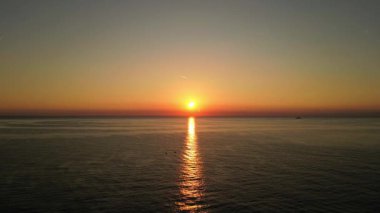 Akdeniz ve güney Fransa 'daki Esterel dağları üzerindeki hava gündoğumu, dalgalı su yüzeyine yansıyan turuncu güneş ışığı, altın gökyüzü ve huzurlu kıyı manzarası