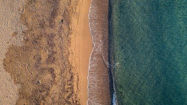 Akdeniz kıyı şeridinin insansız hava aracı görüntüsü turkuaz denizin altın kumla buluştuğu yer, dalgaların ve plajın mükemmel doğal simetrisi..