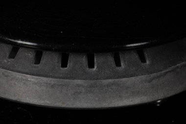 Koyu metal bir gaz ocağına yakın çekim. Slotlarla ızgara, mutfağı temsil eden ve yemek pişiren.