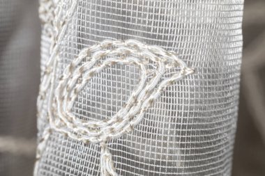 Zarif işlemeli beyaz örgü perde kumaşının aşırı yakın çekimi.