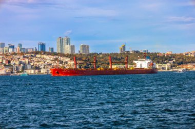 Büyük kırmızı kargo gemisi İstanbul 'un modern siluetini geçerek Boğaz' a doğru yol alıyor.