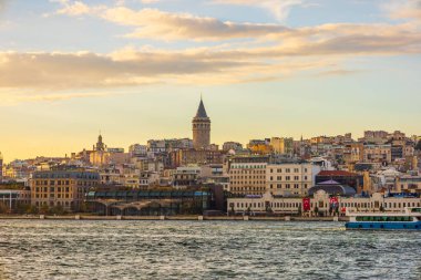 Tarihi Galata Kulesi ve Beyoğlu, altın saat günbatımında Boğaz 'dan gökyüzüne yükseliyor.