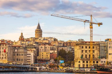 Şehir binalarının üzerinde yükselen Galata Kulesi ve kalkınmayı simgeleyen bir inşaat vinci