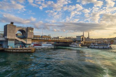 İstanbul 'daki Galata Köprüsü ve Eminonu limanı feribot ve günbatımı ışıklarıyla