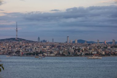 İstanbul Boğazı ve Asya tarafının panoramik manzarası alacakaranlıkta feribot ve Camlica Kulesi ile ufuk çizgisi
