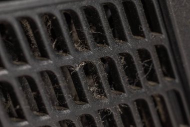 Aşırı yakın plan, yoğun toz ve enkaz tabakasıyla havalandırma kapağını gösteriyor..