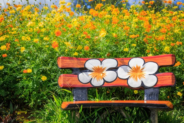 Cement Bench beside Cosmos flowers background.